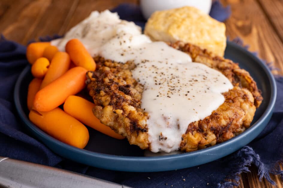 Plate of chicken fried steak with gravy and carrots.