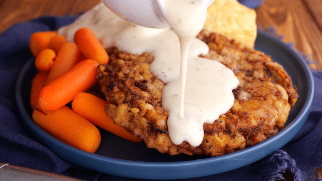 Covering chicken fried steak with gravy.