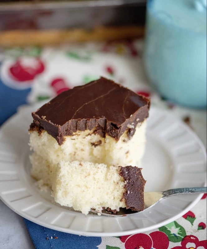 Forkful of white cake with boiled chocolate icing.