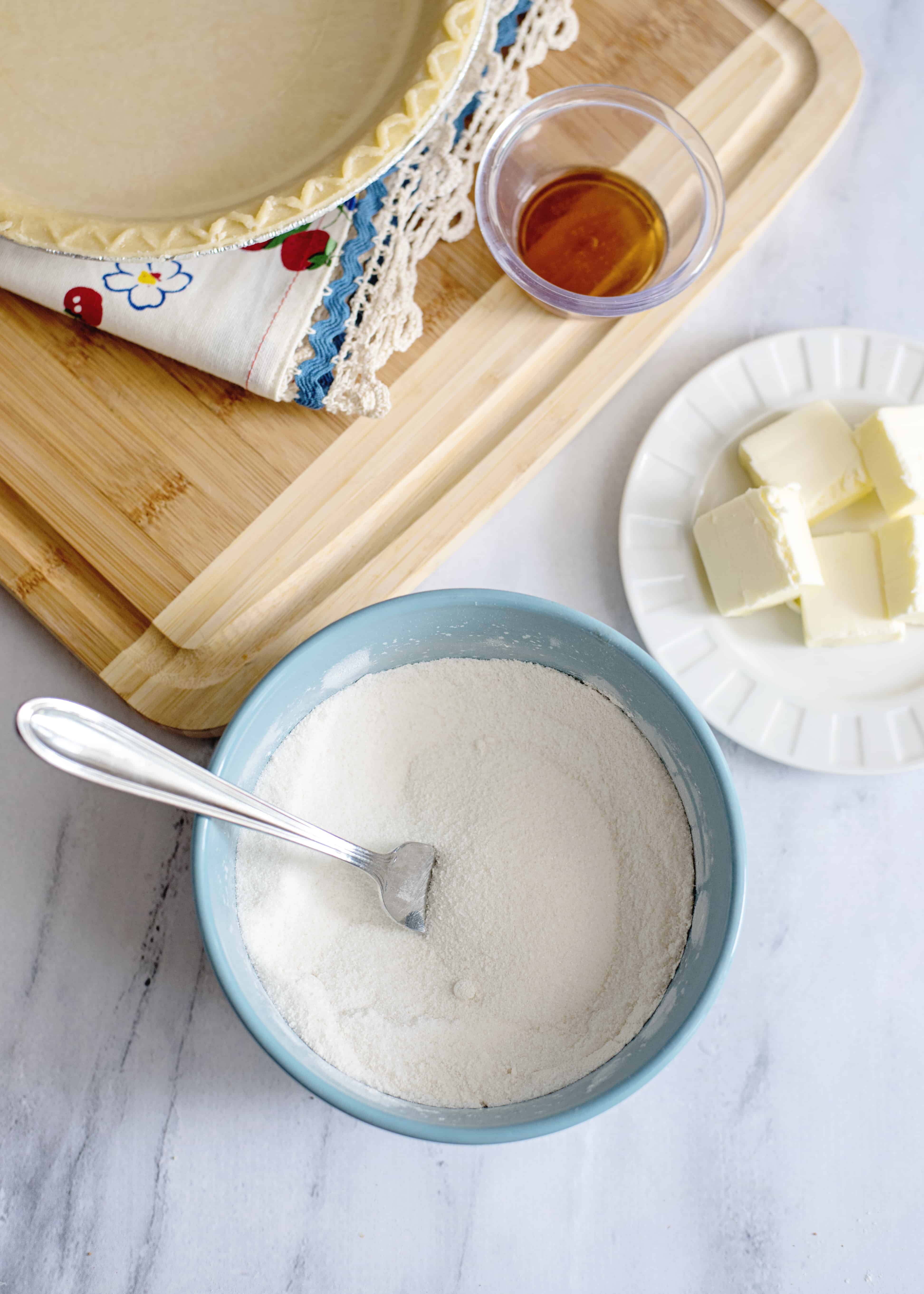 Flour and sugar in a blue bowl with a fork.