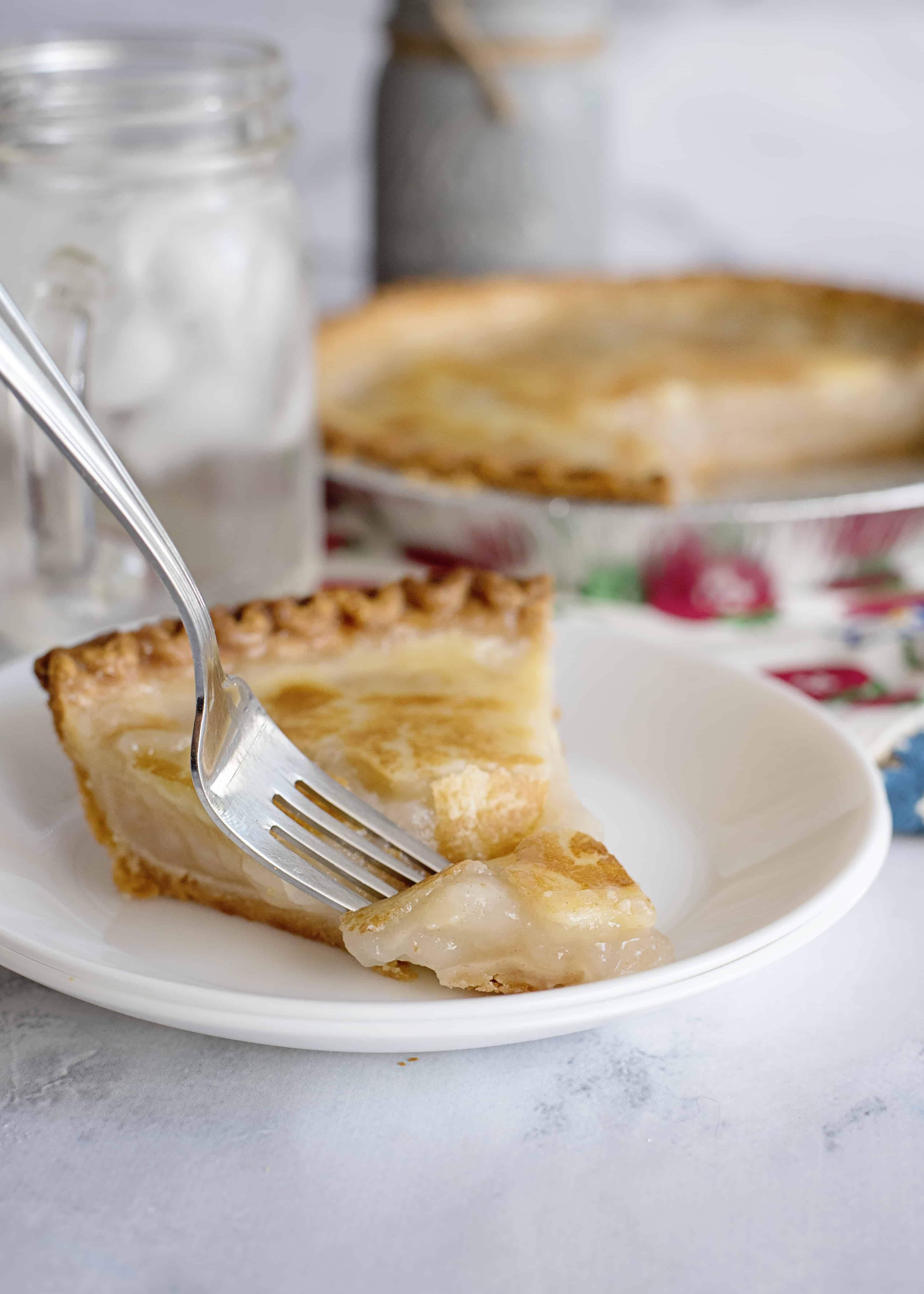 A fork dipping into a slice of water pie on a white plate.