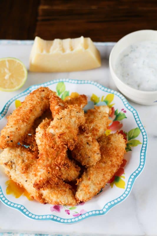 garlic parmesan chicken fingers on a blue rimmed plate 