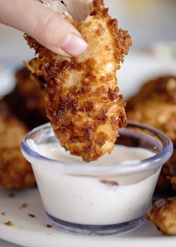 Dipping chicken plank into sauce.