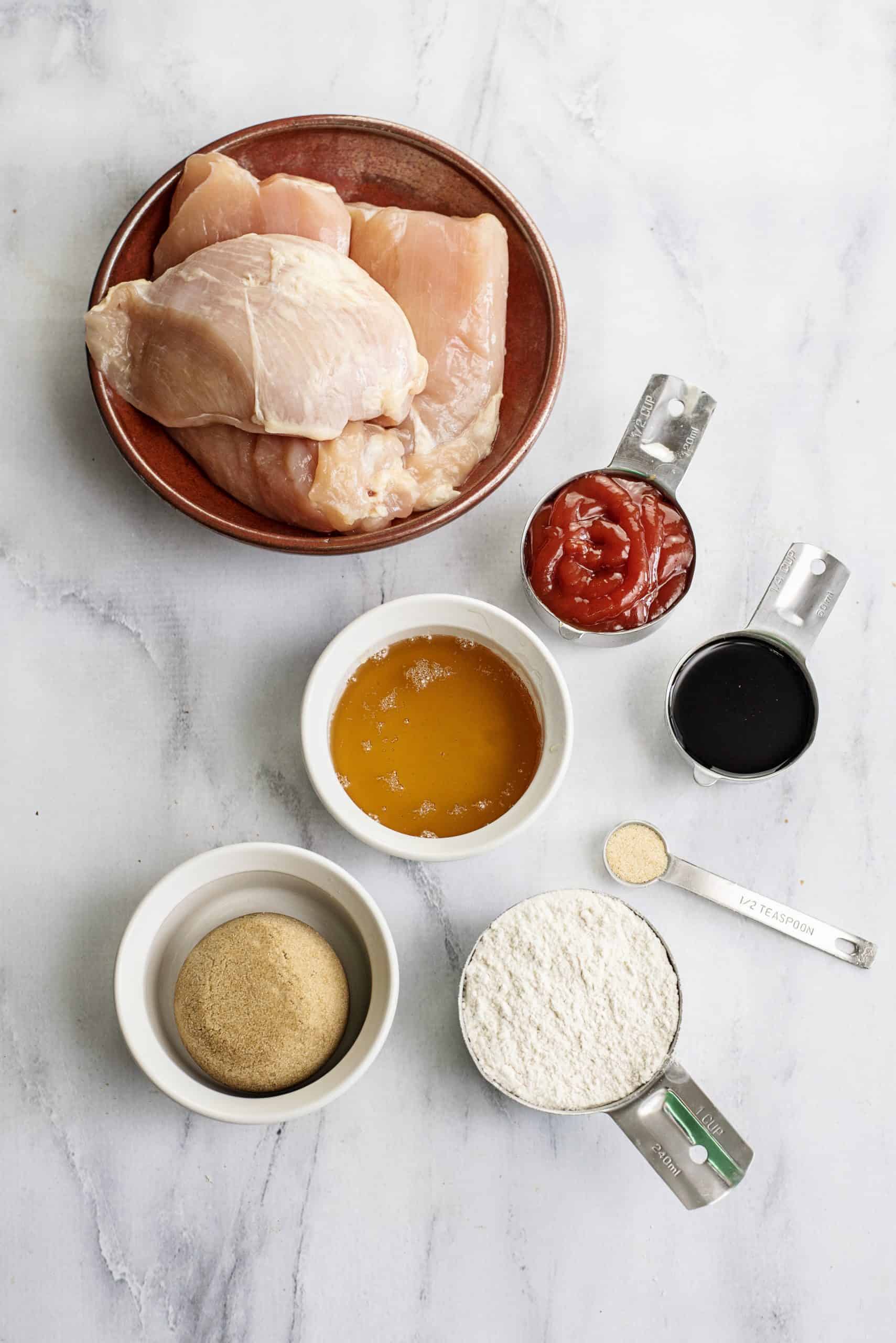 BBQ chicken breast in oven ingredients include boneless, skinless chicken breast, honey, brown sugar, ketchup, soy sauce, garlic powder, and all-purpose flour.