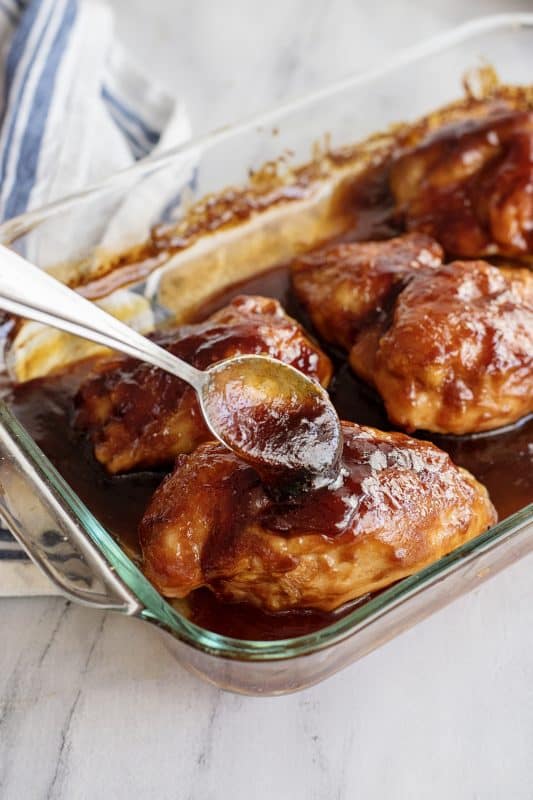 Basting chicken breasts in BBQ sauce.