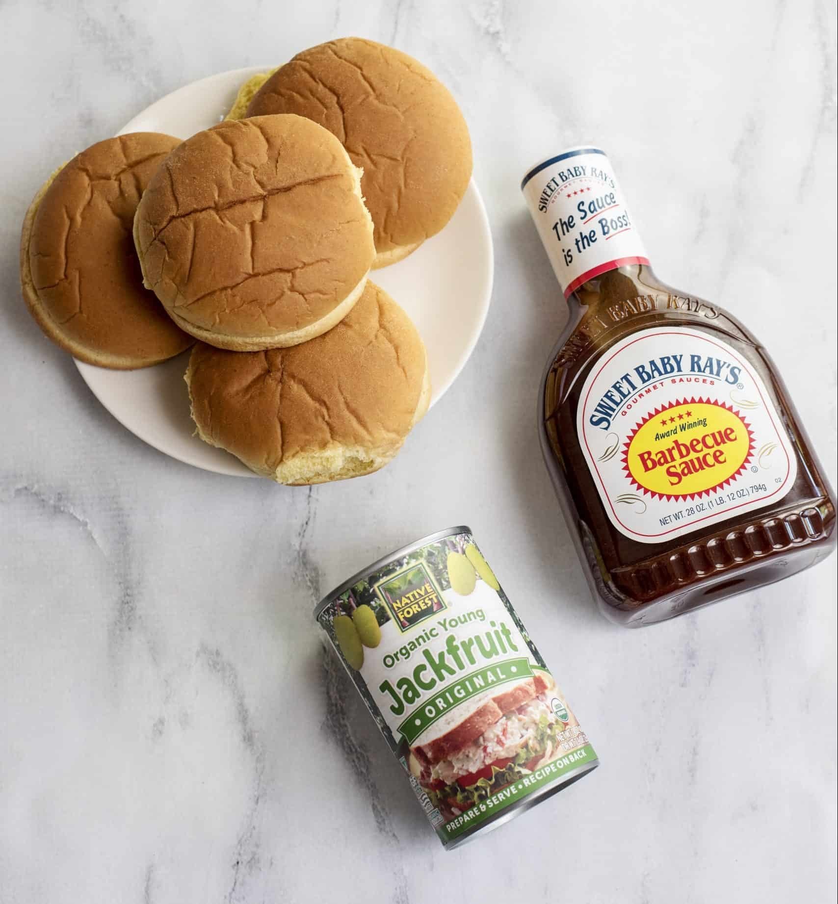 Ingredients for Jackfruit BBQ featuring buns, a can of young green jackfruit, and BBQ sauce.