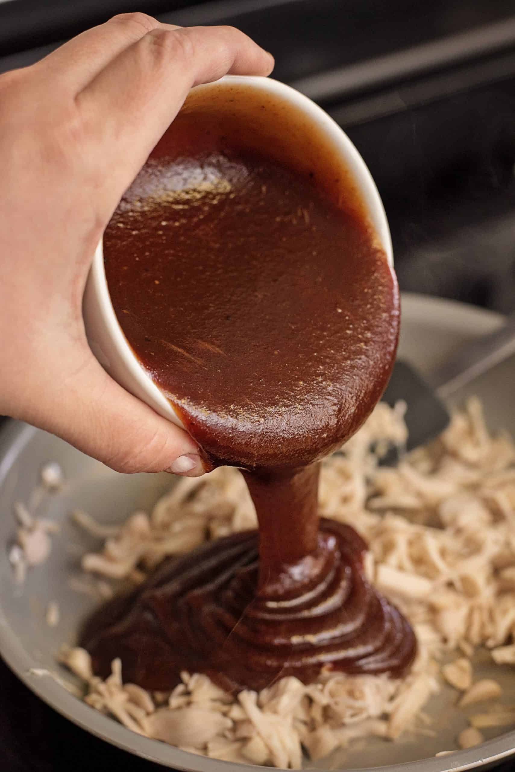 Adding BBQ sauce to jackfuit in a skillet.