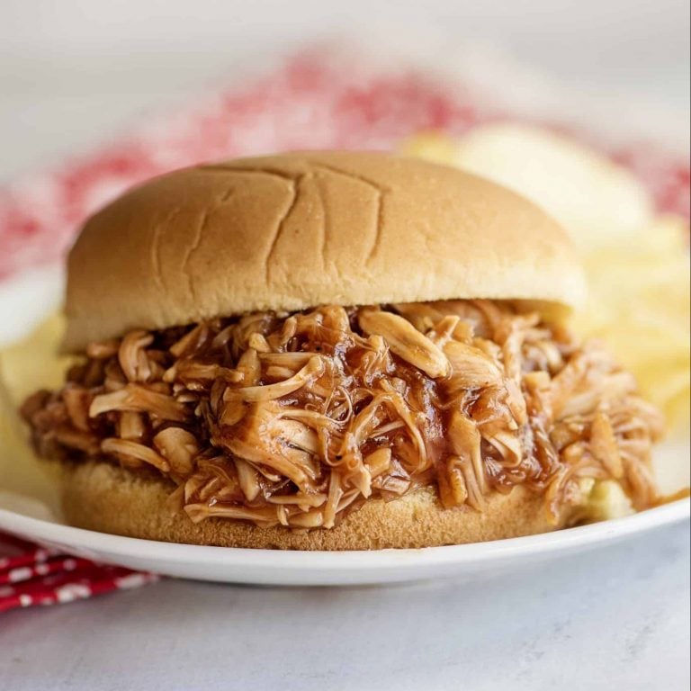 Jackfruit BBQ sandwich on a white plate with a side of potato chips.
