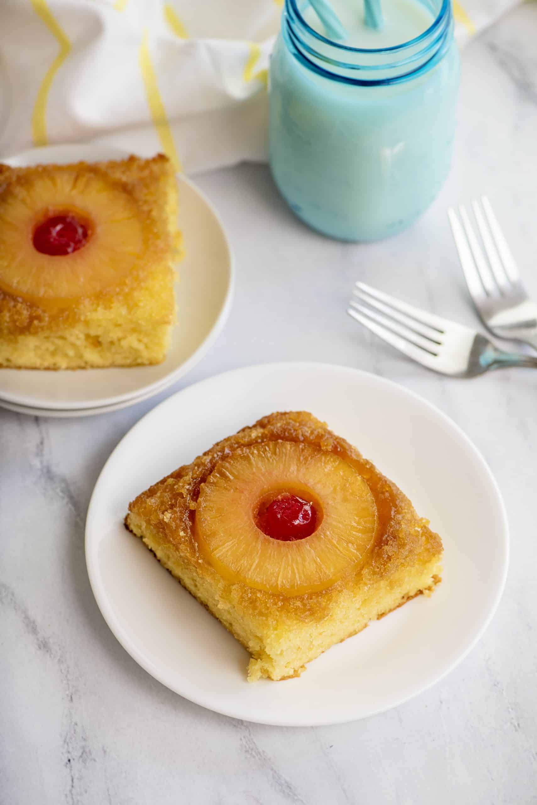 Two slices of pineapple upside-down cake on white plates.