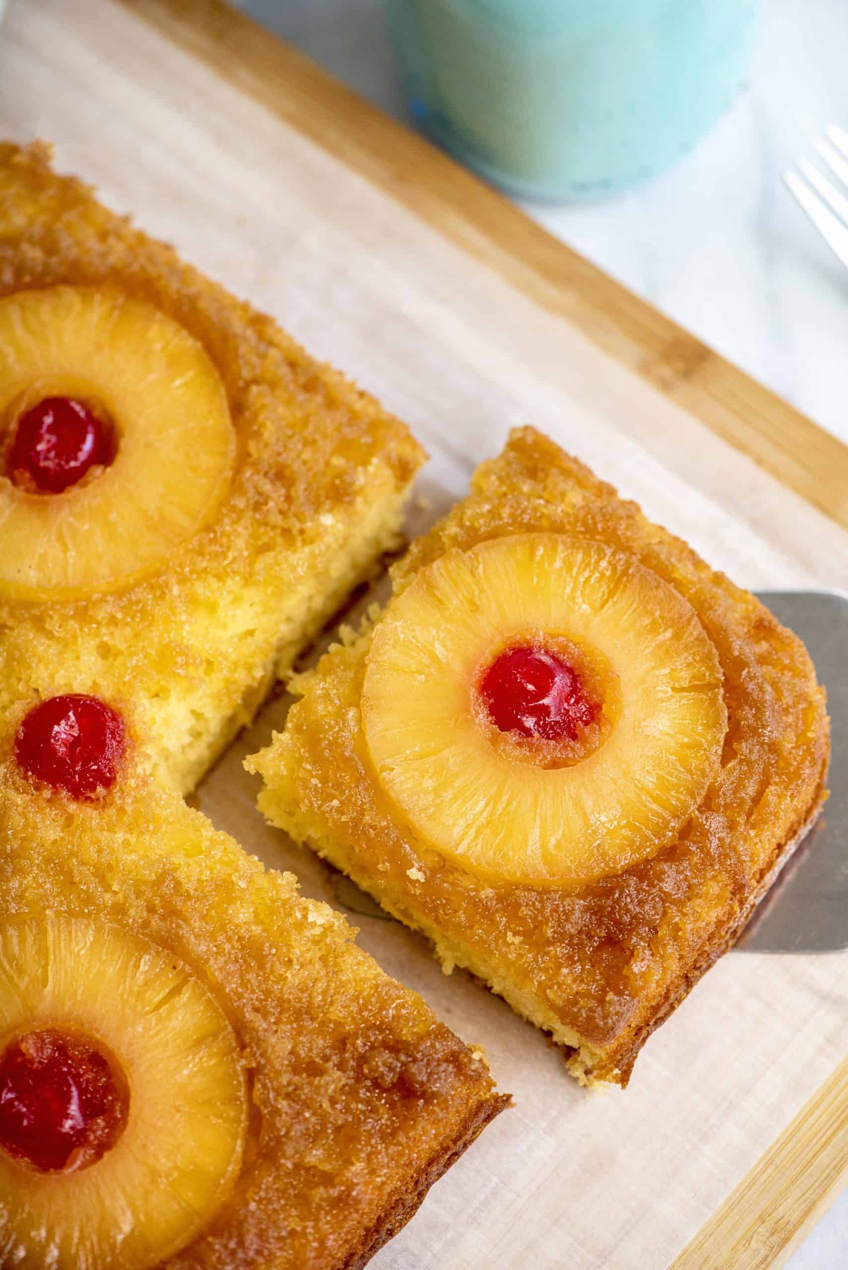 Taking a slice of pineapple-upside down cake with a metal spatula.