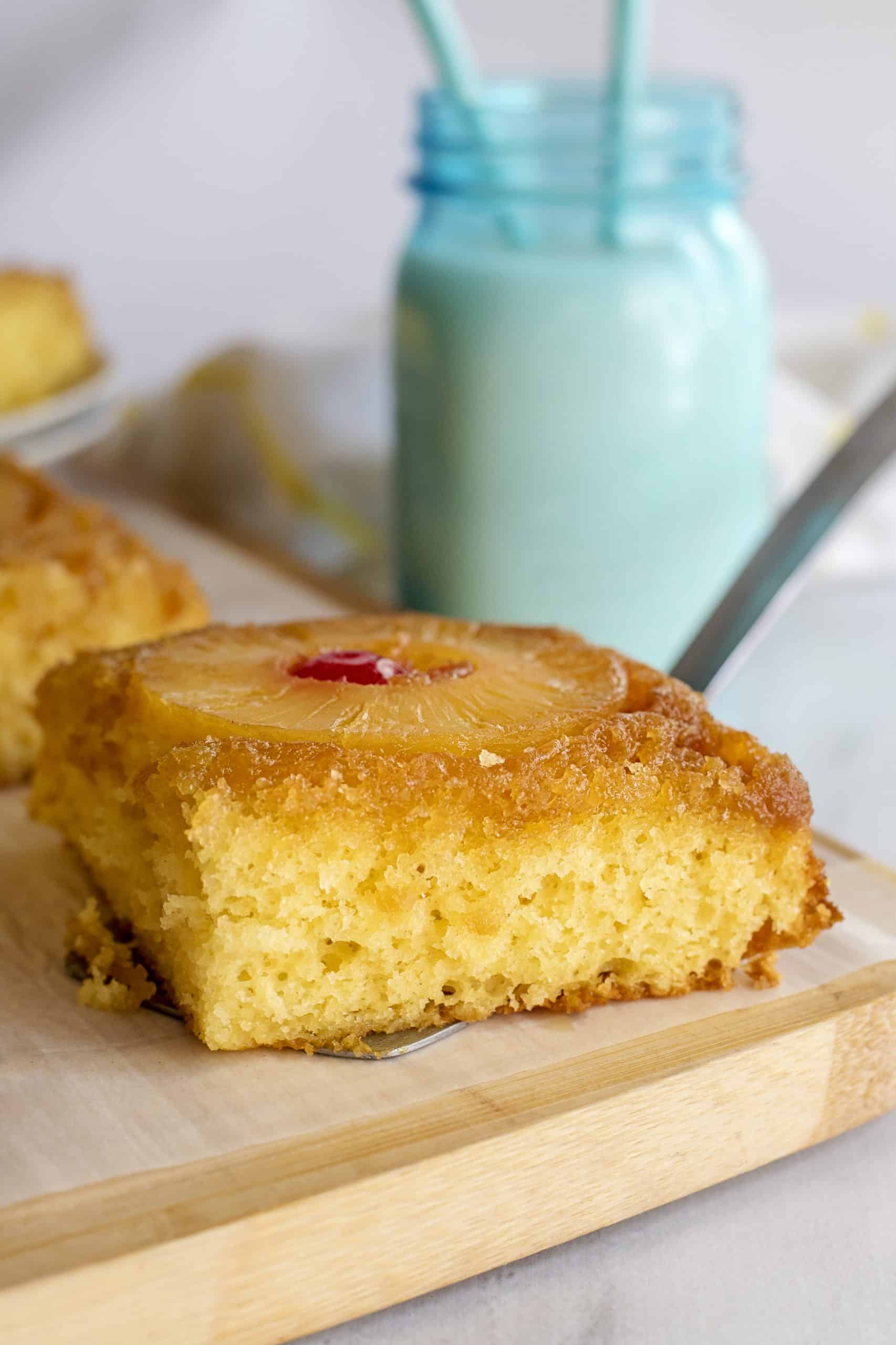 Close-up of pineapple upside-down cake recipe with a glass of milk in the background.