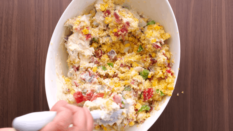 Stirring salad dressing to coat cornbread salad.