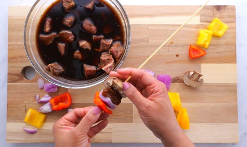 Skewering steak and veggies on kabob sticks.