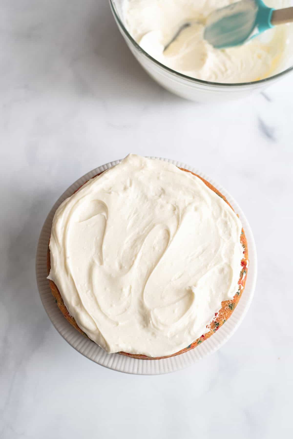 Easy Peasy Birthday Cake From Scratch Icing spread on first layer of the birthday cake.
