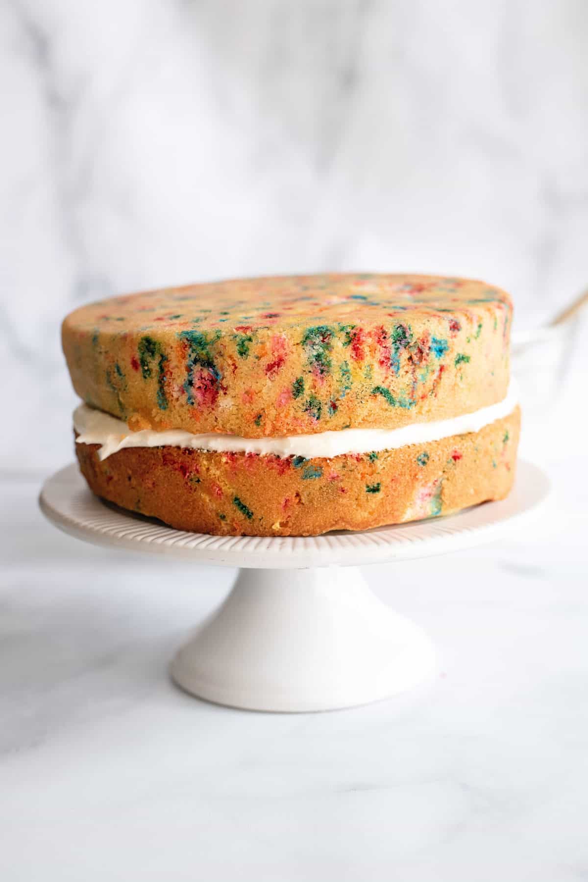 Easy Peasy Birthday Cake From Scratch Icing between two birthday cake layers.