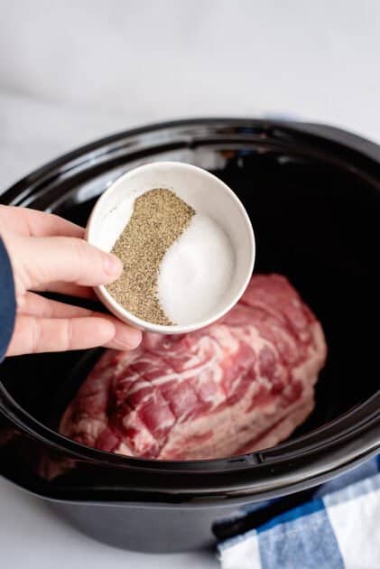 Place pork roast and salt and pepper in slow cooker.