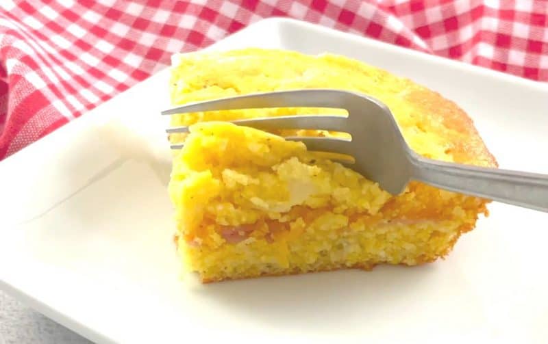 Fork slicing into slice of Jiffy cornbread casserole.