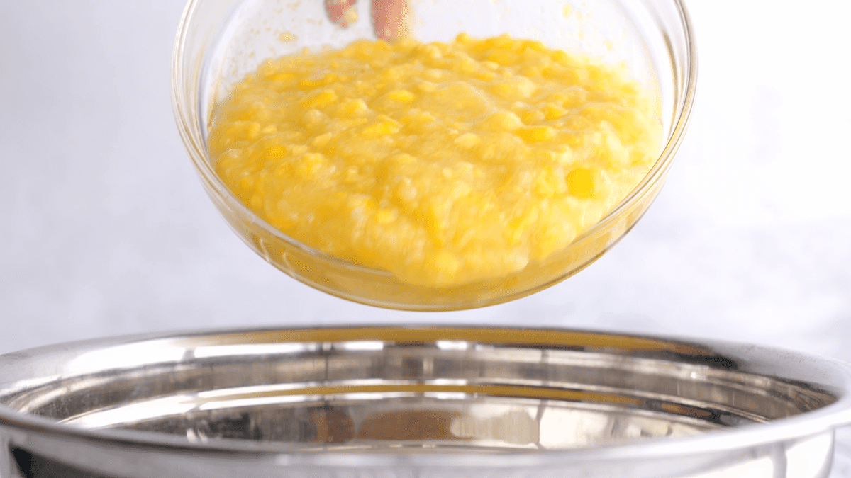 Adding corn to the mixing bowl.