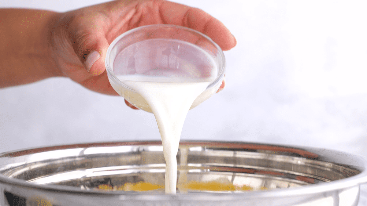 Adding milk to the mixing bowl.