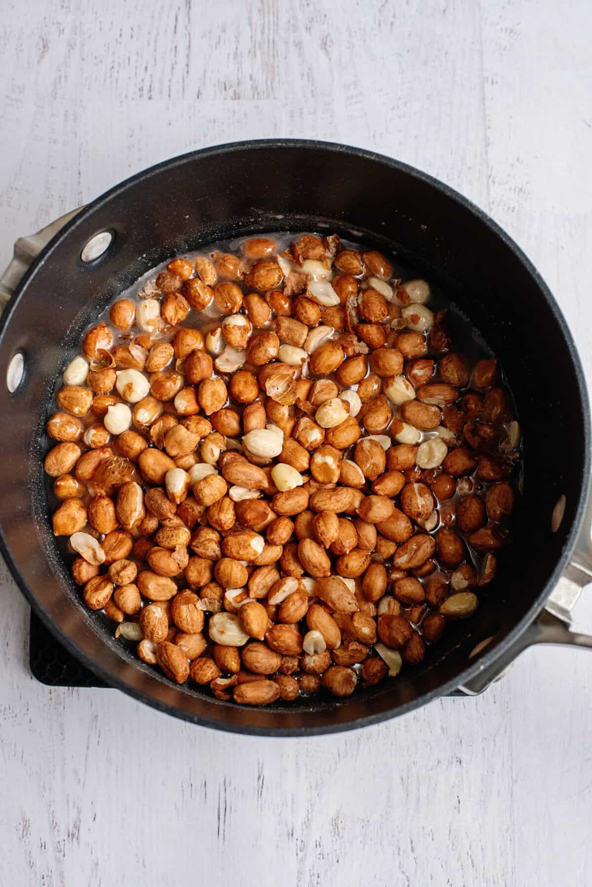 Raw peanuts in a large pot with sugar.