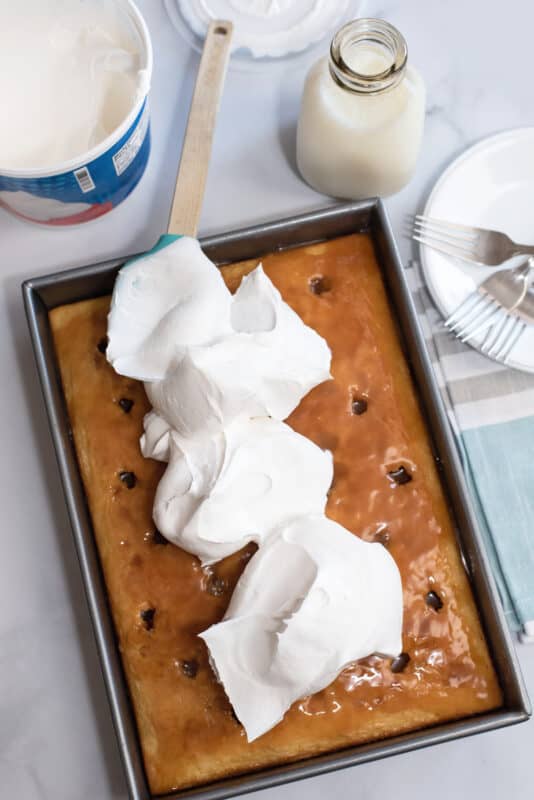 Dollops of whipped cream over cuatro leches cake.