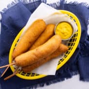 Basket of corn dogs with mustard.