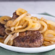 Hamburger steaks on plate topped with lots of fried onions.