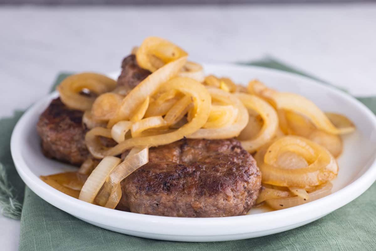 Hamburger steaks on plate topped with lots of fried onions.