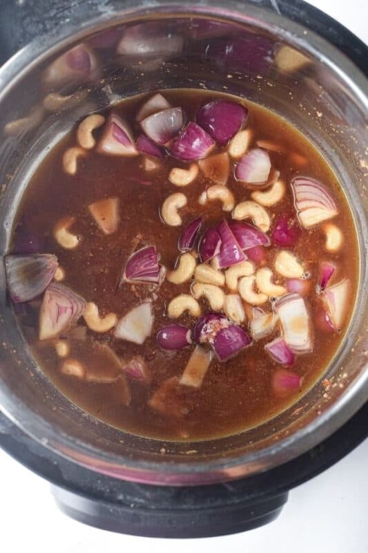 Add cashew, onions, and water to pressure cooker.