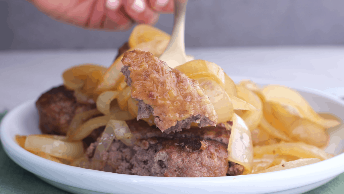 Forkful of hamburger steak with fried onions.