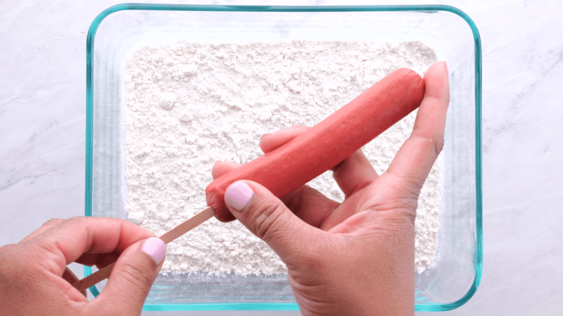 Dump plain flour into bowl and skewer each weenie.