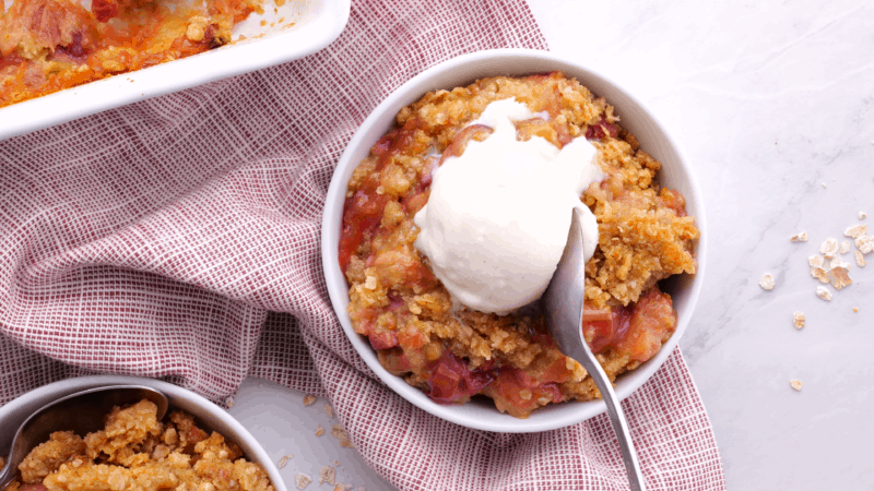 Spoon in bowl of rhubarb crisp.