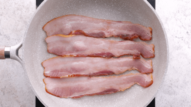 Frying bacon in skillet.