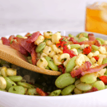 Wooden spoon scooping out serving of succotash.