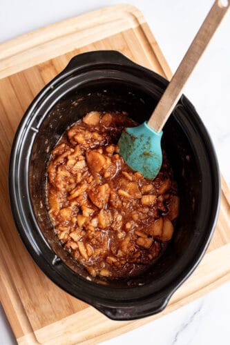 Stirring sugar and spices into applesauce in crockpot.