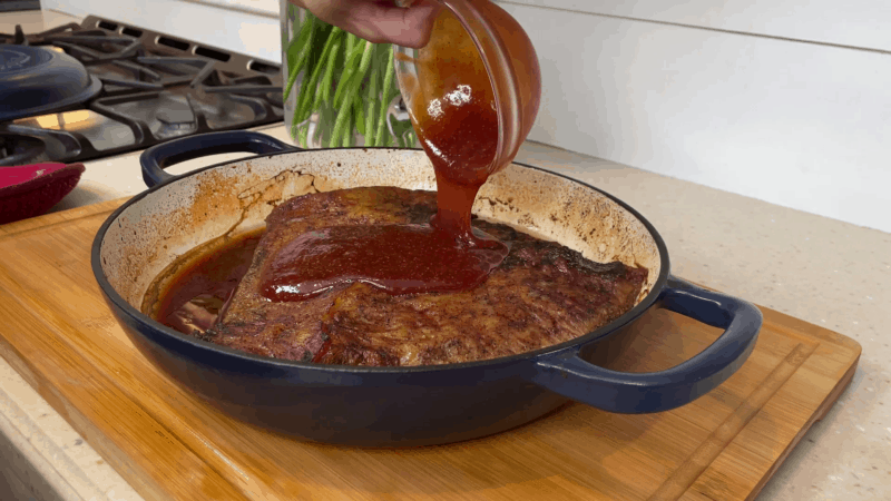 Pouring sauce over cooked beef brisket.