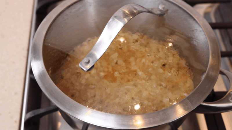 Lid over boiling rice in large poit.