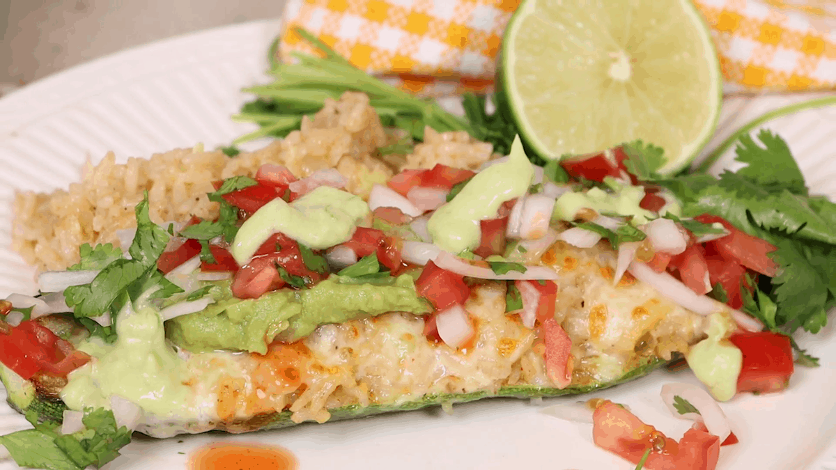 Vegetarian stuffed zucchinis topped with guacamole and pico de gallo.