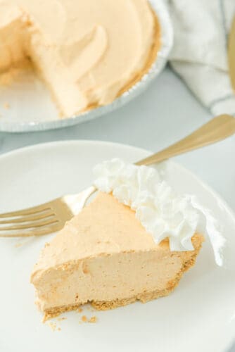 Slice of no-bake pumpkin cheesecake with whipped cream topping.