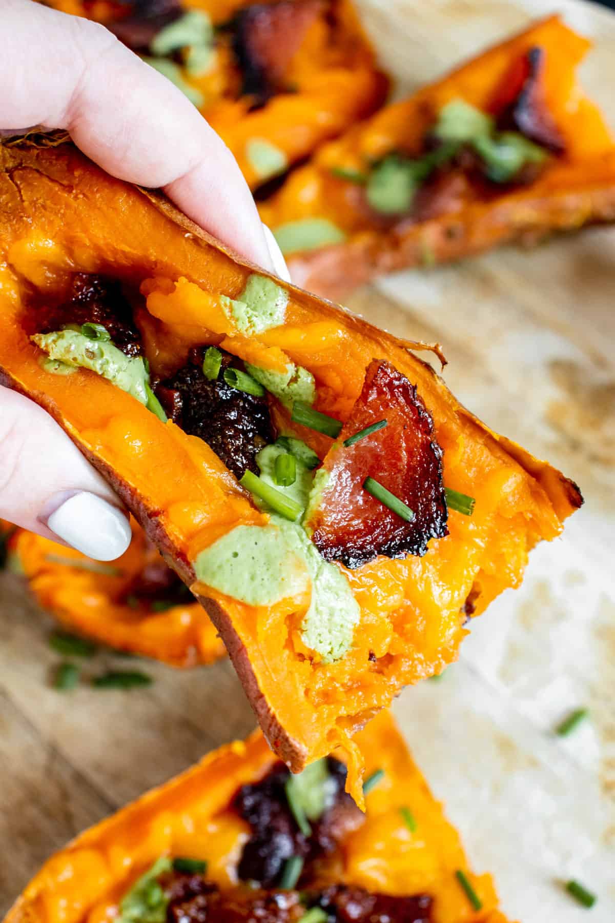 Hand holding a loaded sweet potato skin.