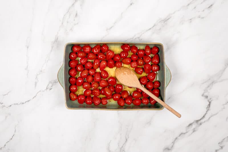Cherry tomatoes and seasoning in oven tray.