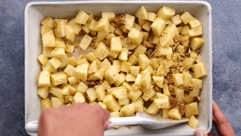 Mixing crumble topping into apple mixture.