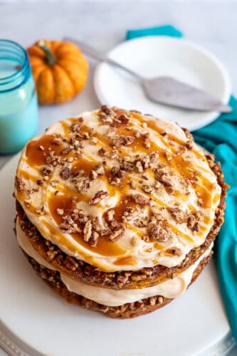 Pumpkin praline cake drizzled with caramel and topped with pecans.