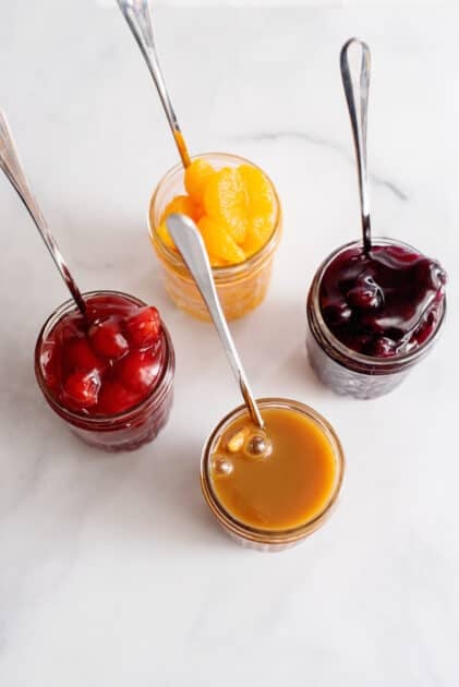 Selection of cheesecake toppings in jars.