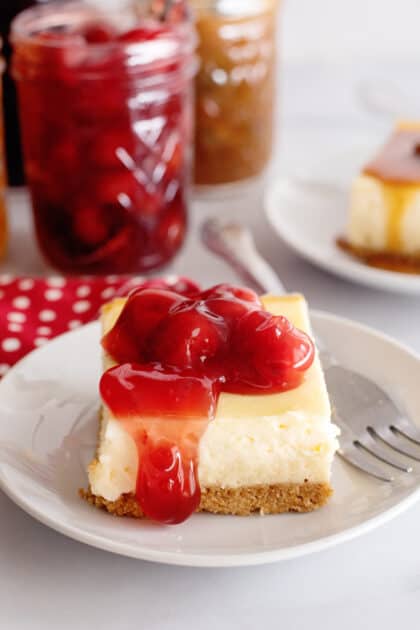 Slice of cheesecake with cherry pie filling topping.