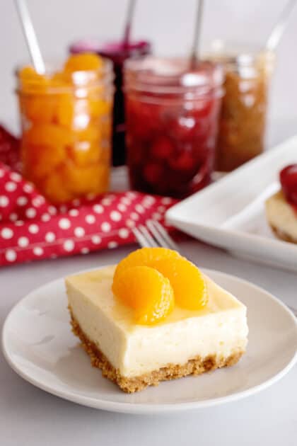 Slice of cheesecake with mandarin oranges on top.