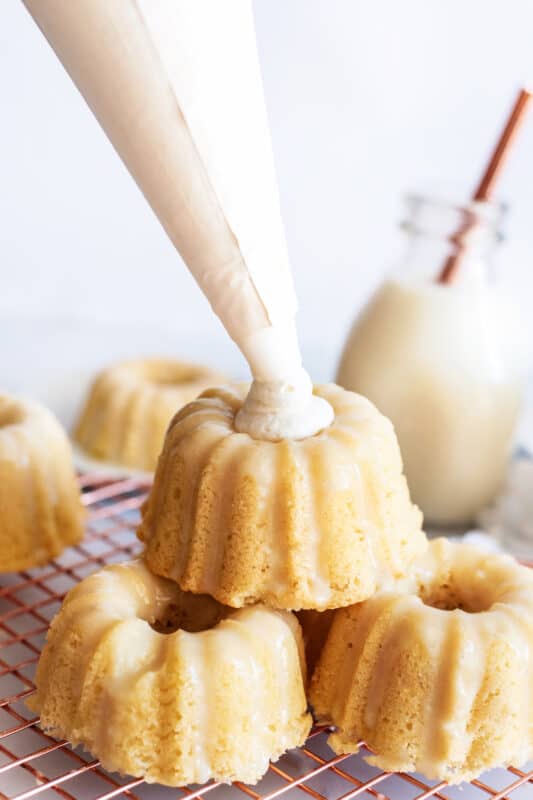 Add dollop of whipped cream to glazed mini cakes.