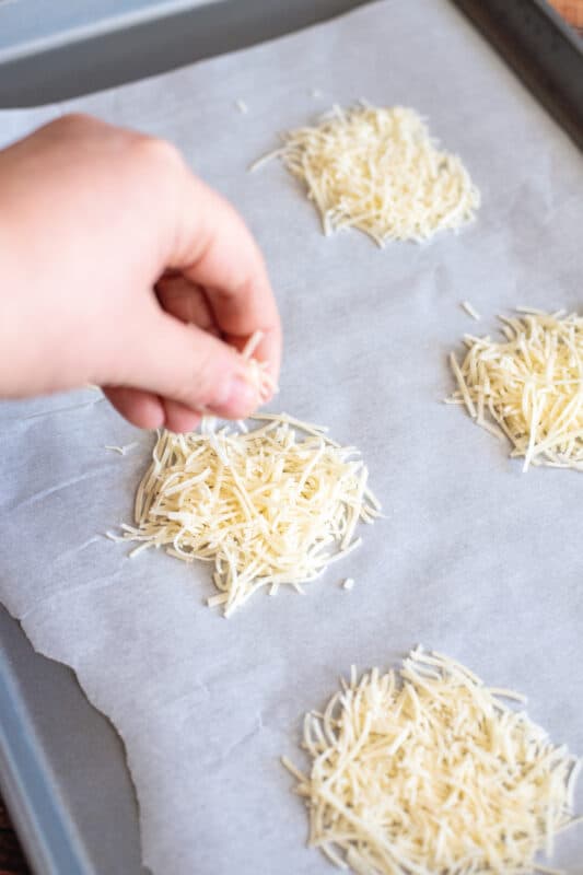 Place parmesan cheese in piles on baking sheet.