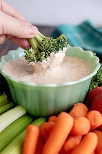 Dipping broccoli floret in chipotle ranch dressing.