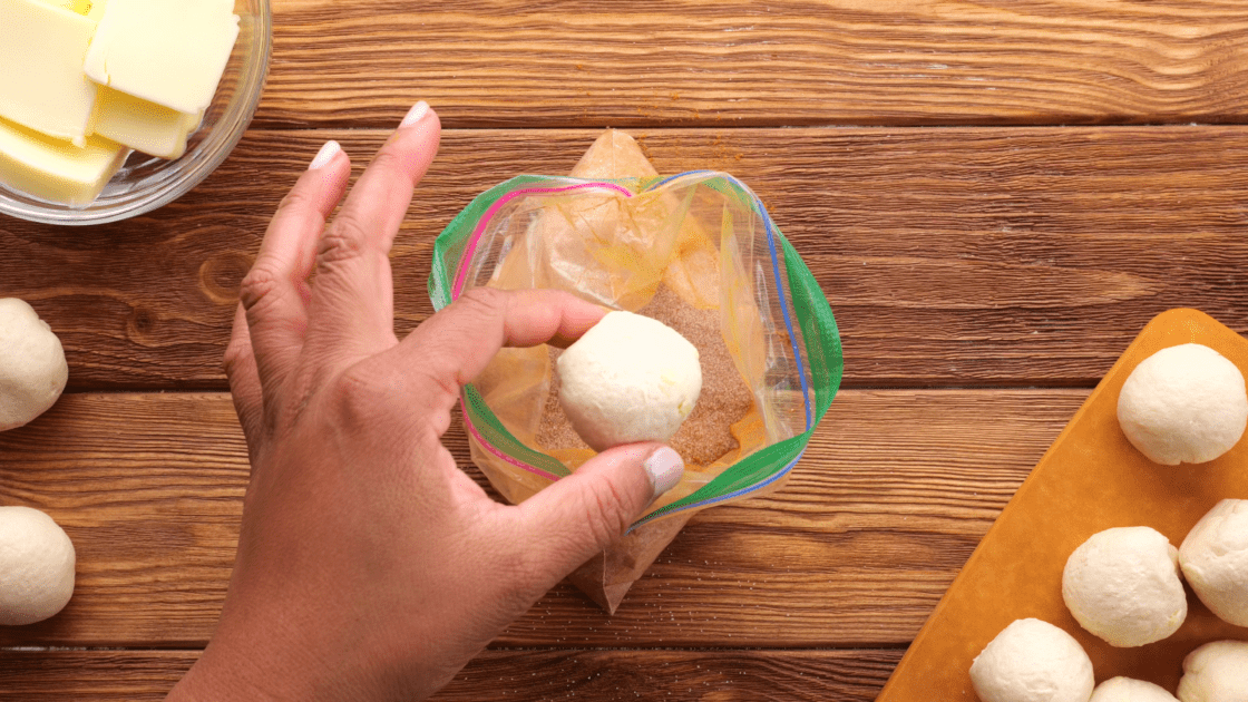 Drop biscuit dough balls into cinnamon sugar and toss to coat.